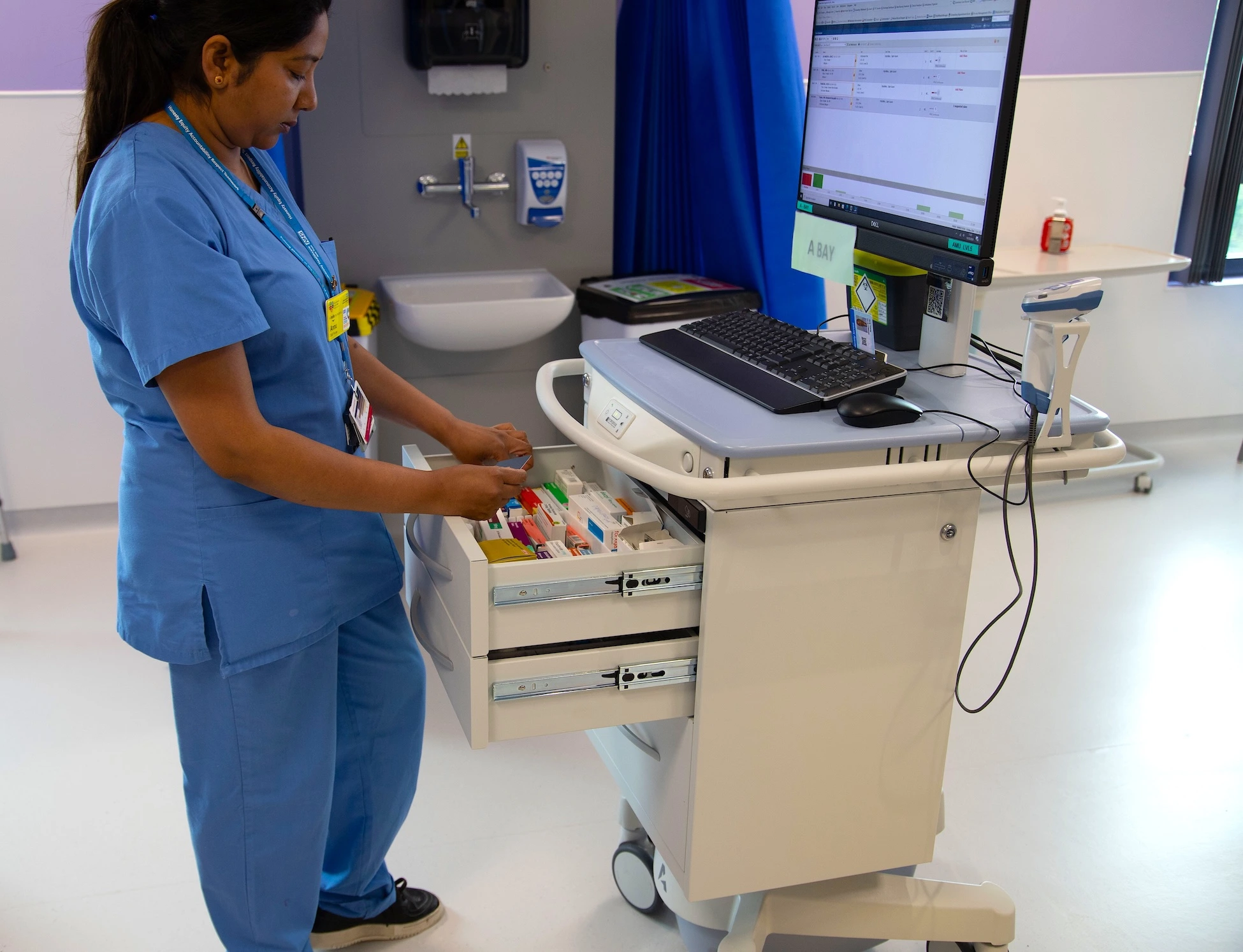 Nurse removing medication from the built in drawers on an Exura cart